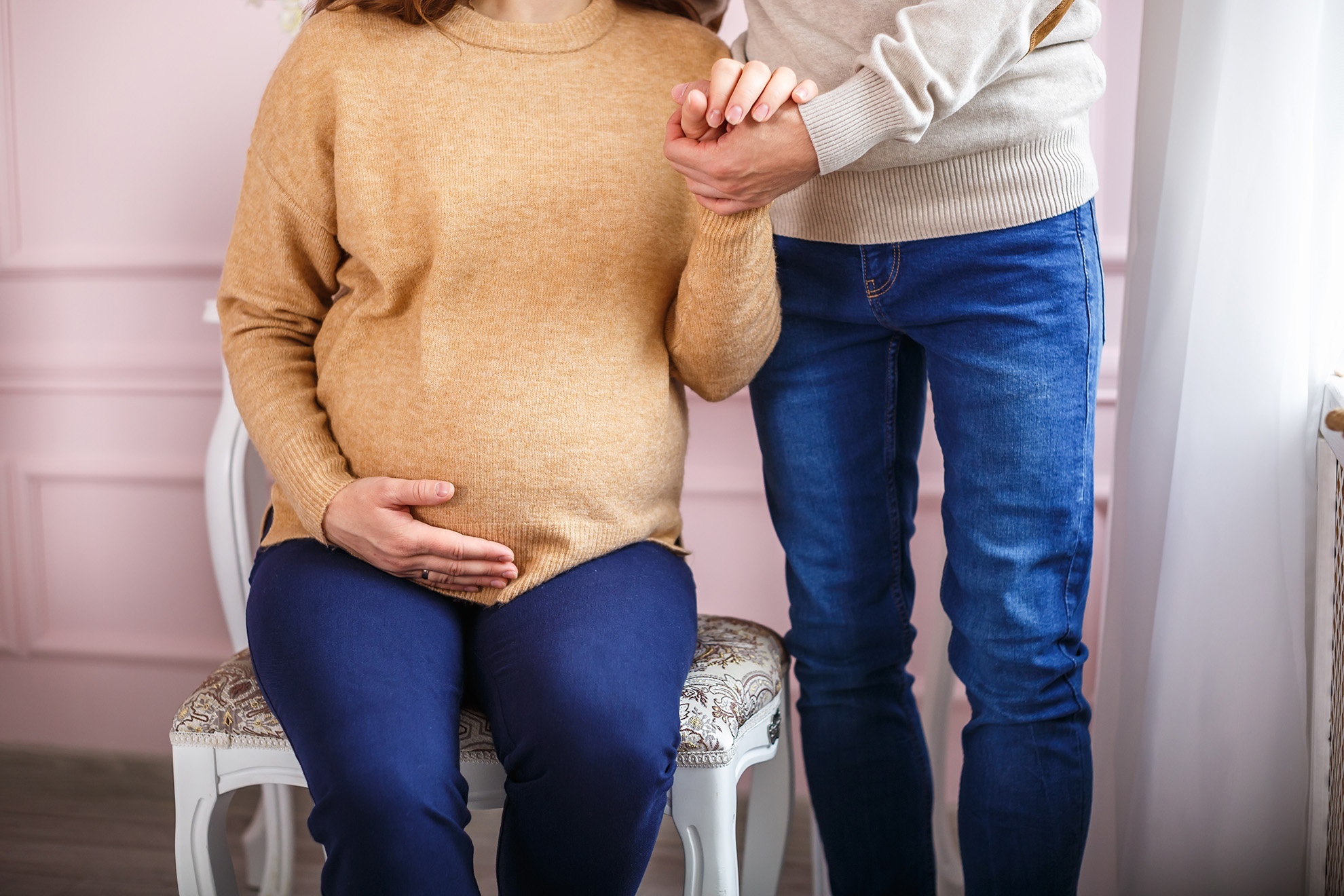 Woman with obvious stress on a couch with one hand to her forehead and the other arm wrapped around her legs.